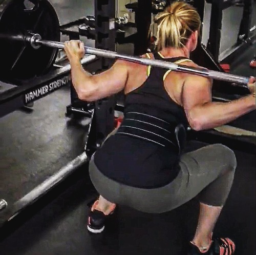 woman squatting with barbell on back