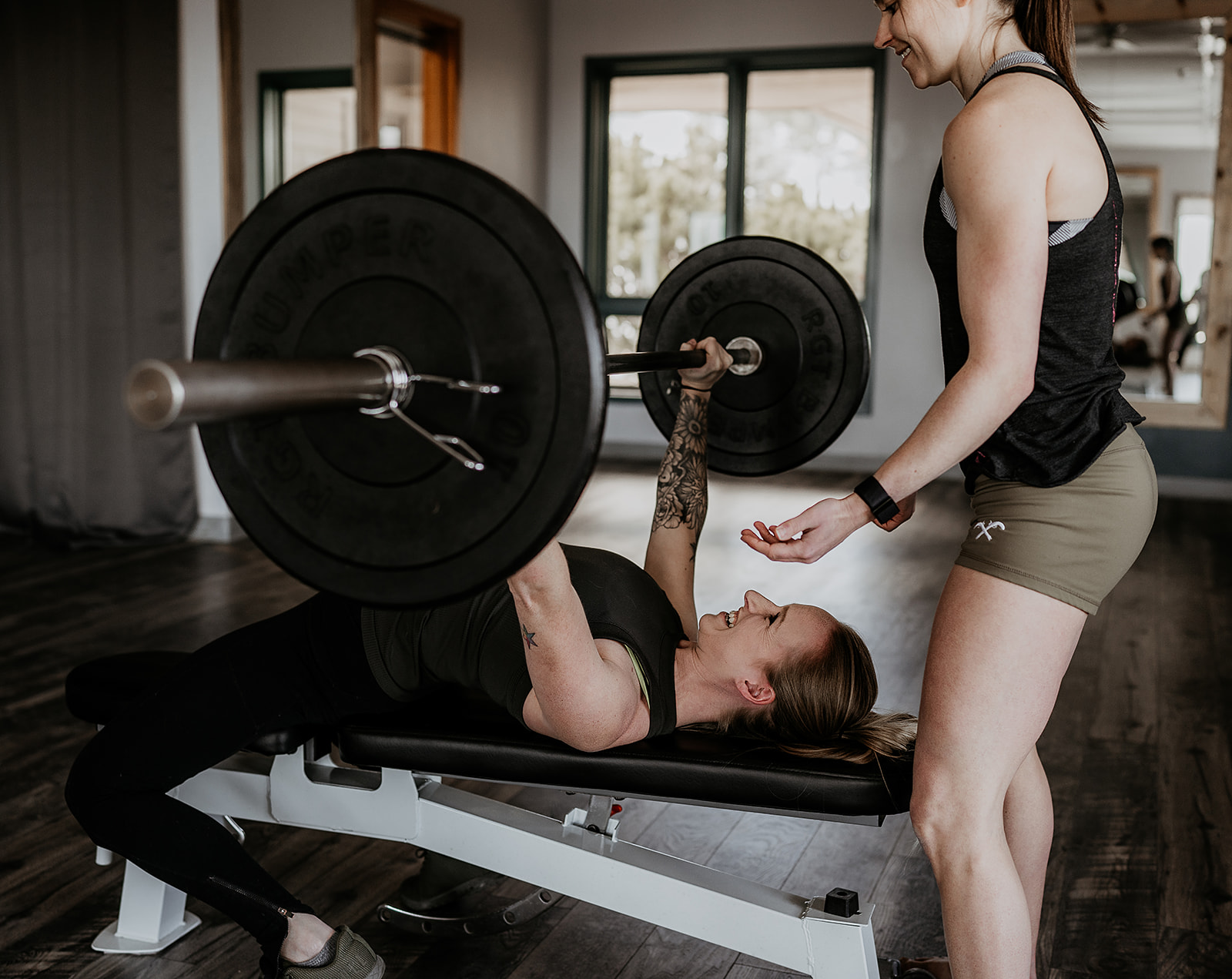 trainer spotting woman on bench press