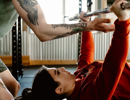 Woman doing bar press with spotter