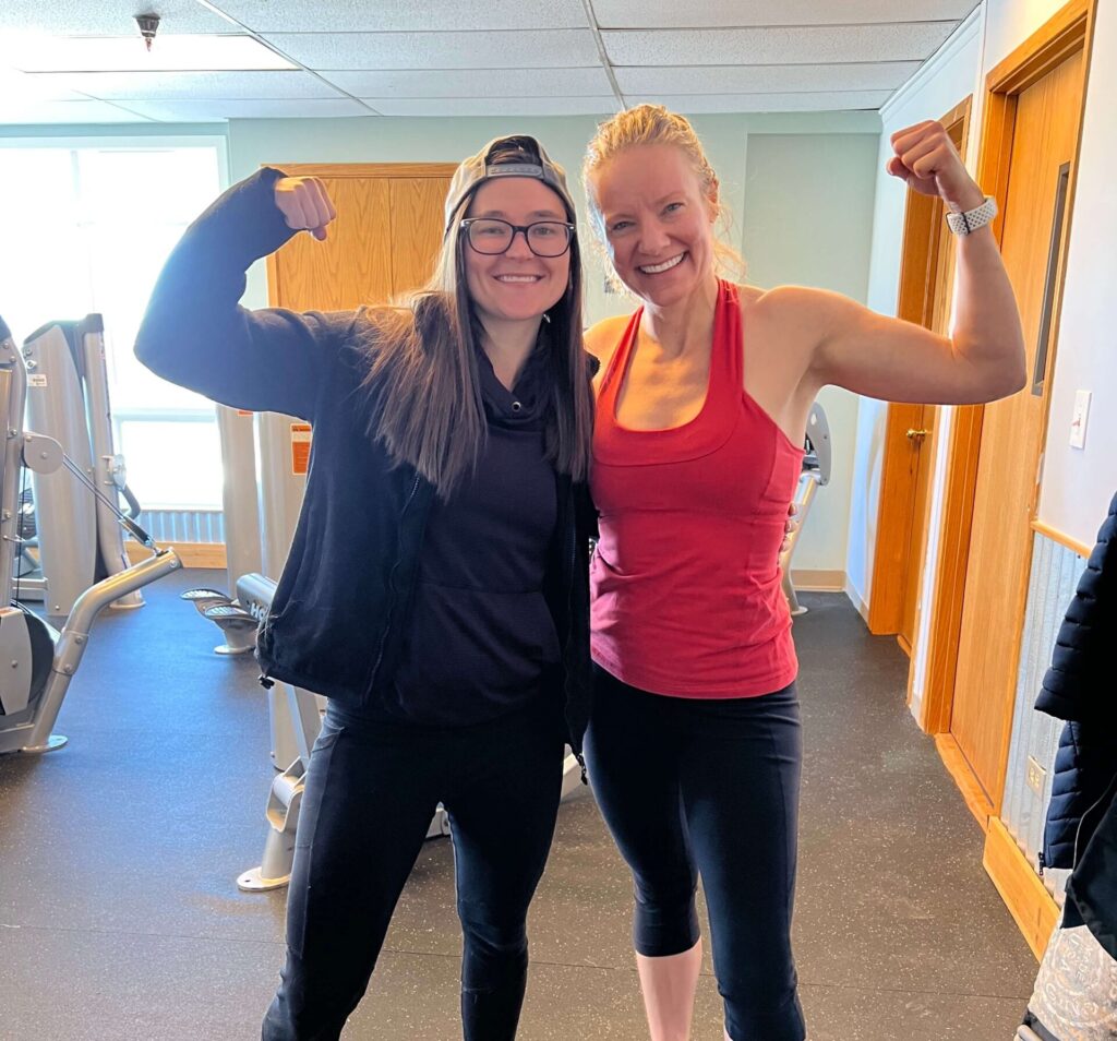 Trainer Katie and Client Bobbi Jo flexing at gym in Golden, Colorado
