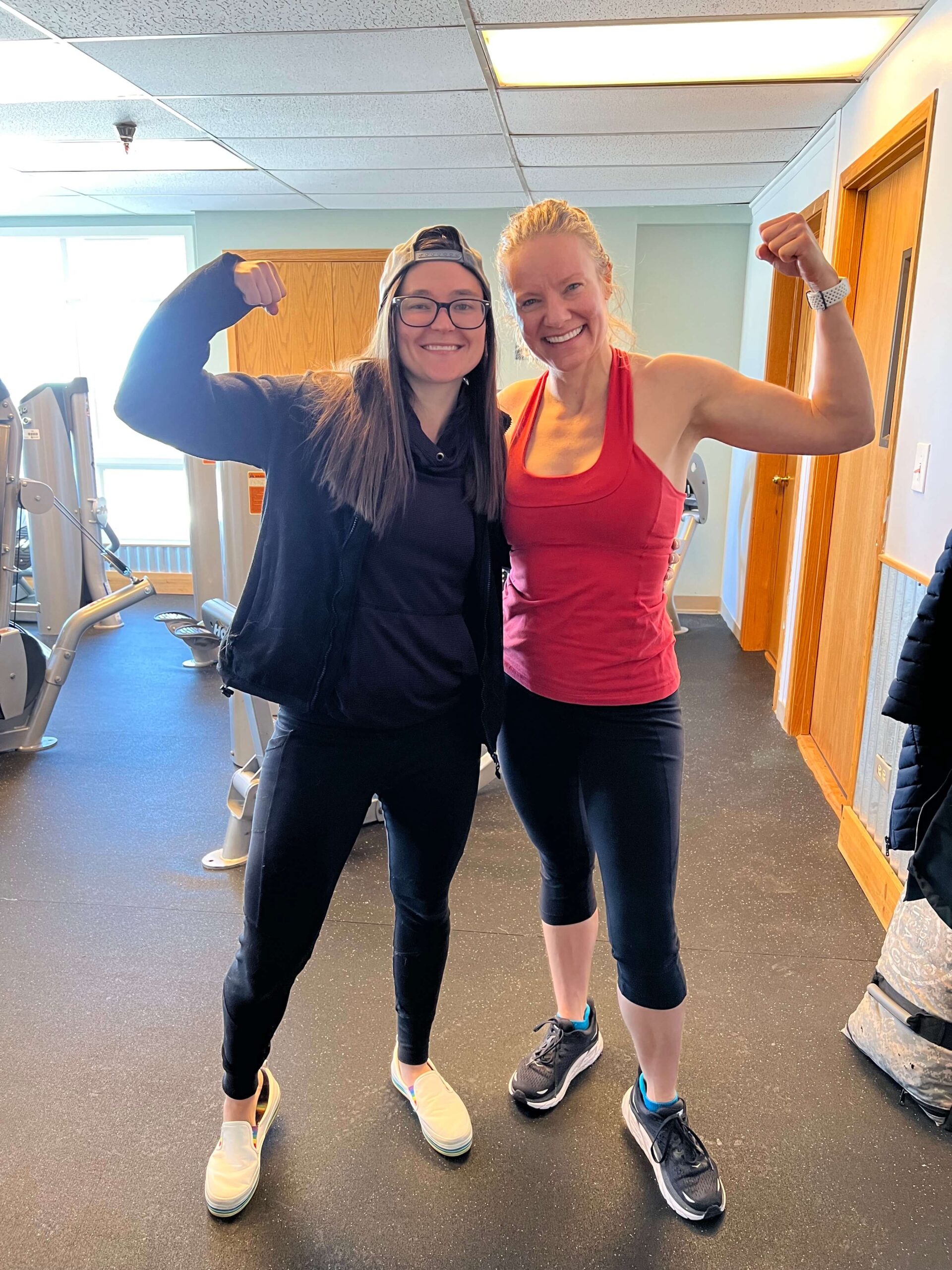 Trainer Katie and Client Bobbi Jo flexing at gym in Golden, Colorado