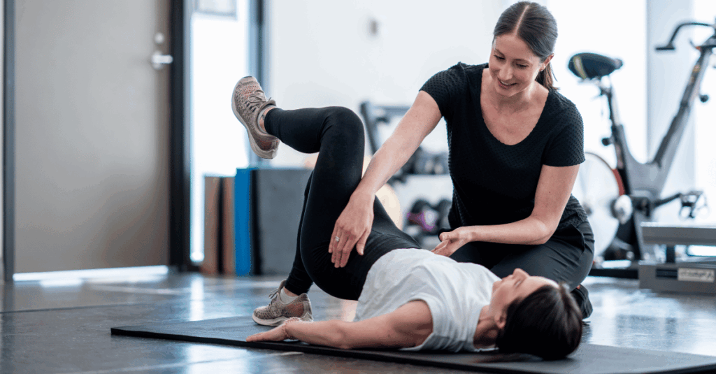 Pelvic floor therapist helping a client with a single leg glute bridge during session